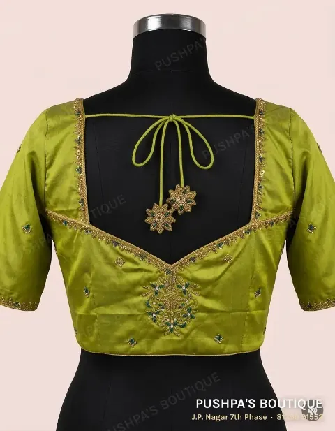A green princess cut blouse with hand embroidery along the square neckline and a hand-worked motif at the centre front
