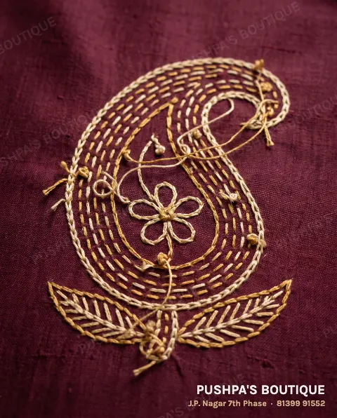 The back of hand aari embroidery: small knots, loose thread tails, threads travelling between parts of the motif, and the reverse of chain stitch as short dashes