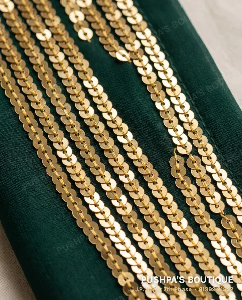 Close-up of machine sequin embroidery on green georgette: gold sequins in perfectly straight overlapping rows, each attached by the same stitch