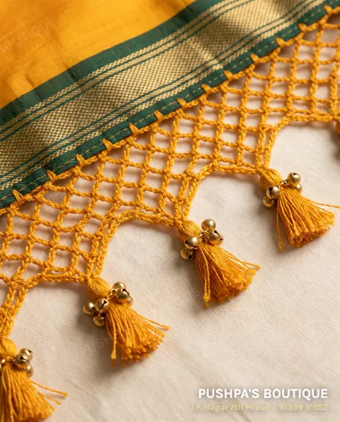 Mango-yellow silk saree pallu with crochet kuchu: a crocheted net of loops ending in tassels with gold bells