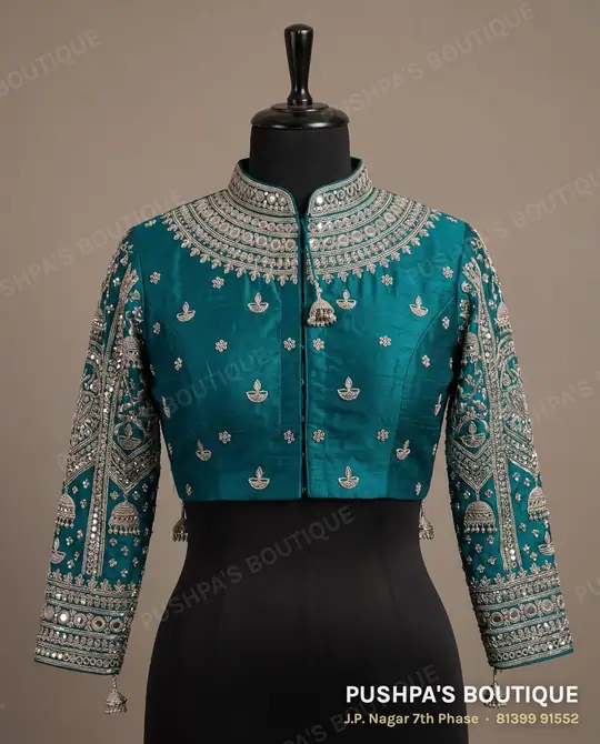 Teal designer blouse with a high neck and full sleeves covered in mirror, sequin and zari work